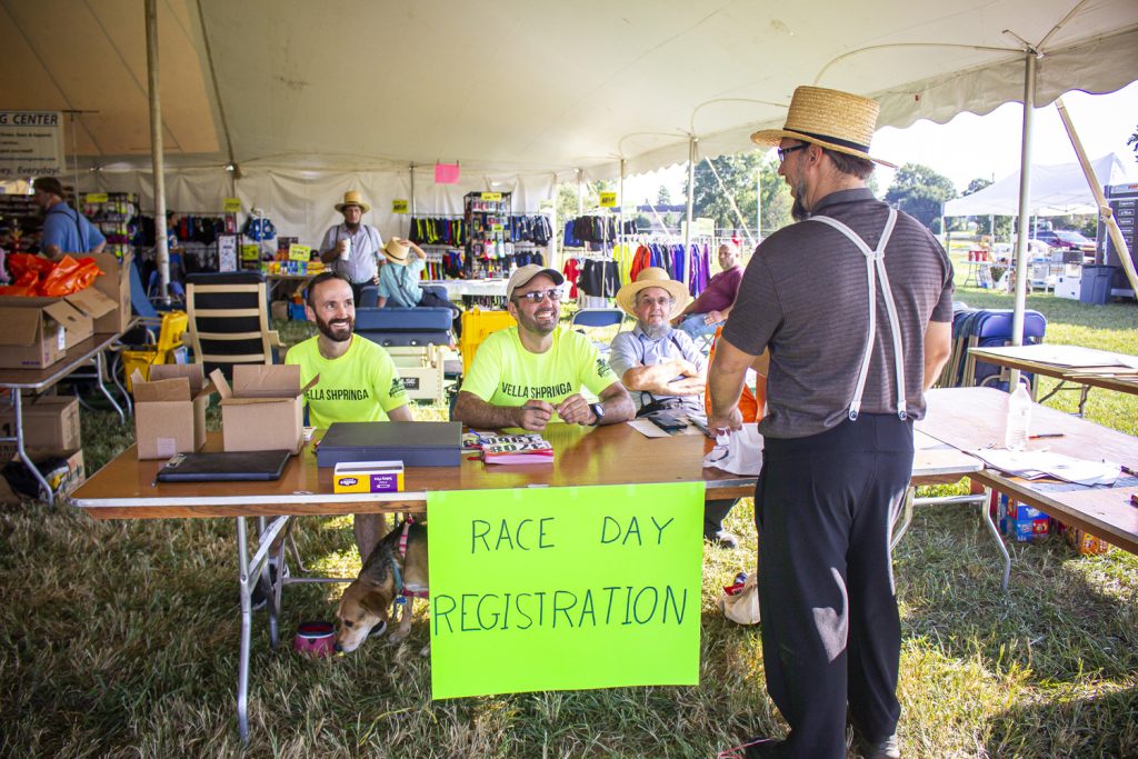 Volunteers gather under the big tent to welcome runners during on-site registration for the Bird-in-Hand Half Marathon