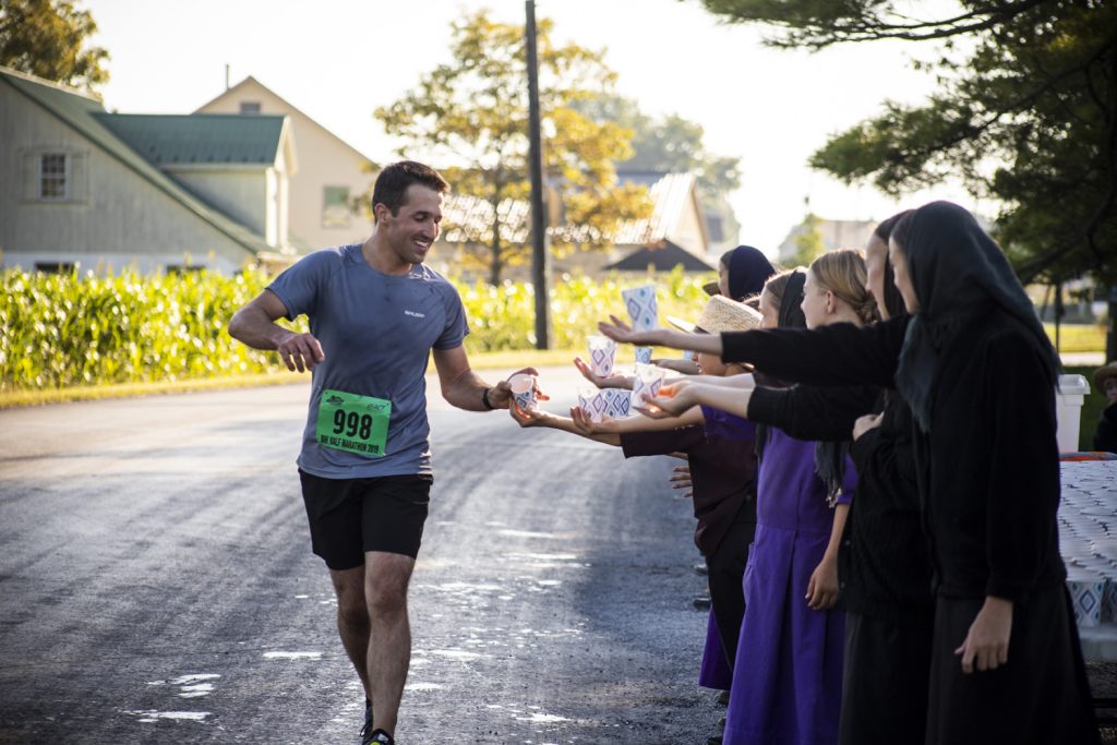 Volunteers hold out water as runners pass throughout the Bird-in-Hand Half Marathon course